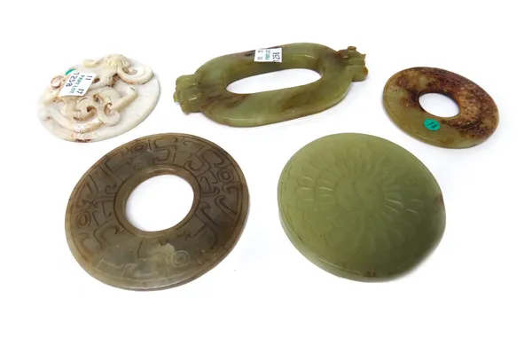 Five Chinese jade carvings, various colours, comprising; a circular dragon disc, 7cm.diameter; an oval disc with animal handles, 12cm. wide; two archa