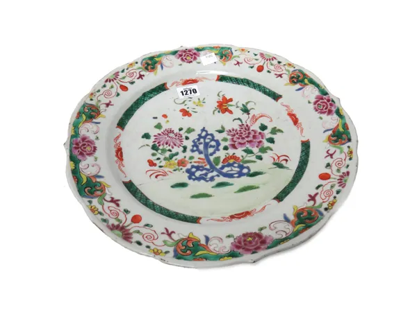 A large Chinese famille-rose plate, Qianlong, painted with flowering shrubs and pierced blue rocks beneath a floral border and shaped rim, 33.5cm. dia