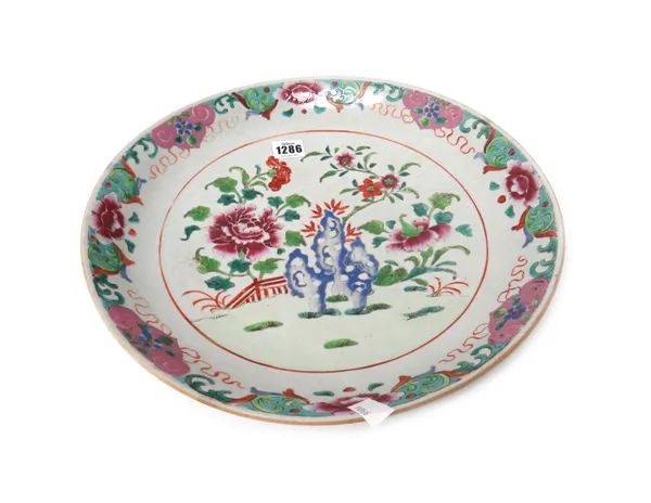 A Chinese famille-rose dish, late 18th century, painted with flowering shrubs and pierced blue rocks in a fenced garden beneath a floral border, 36cm.