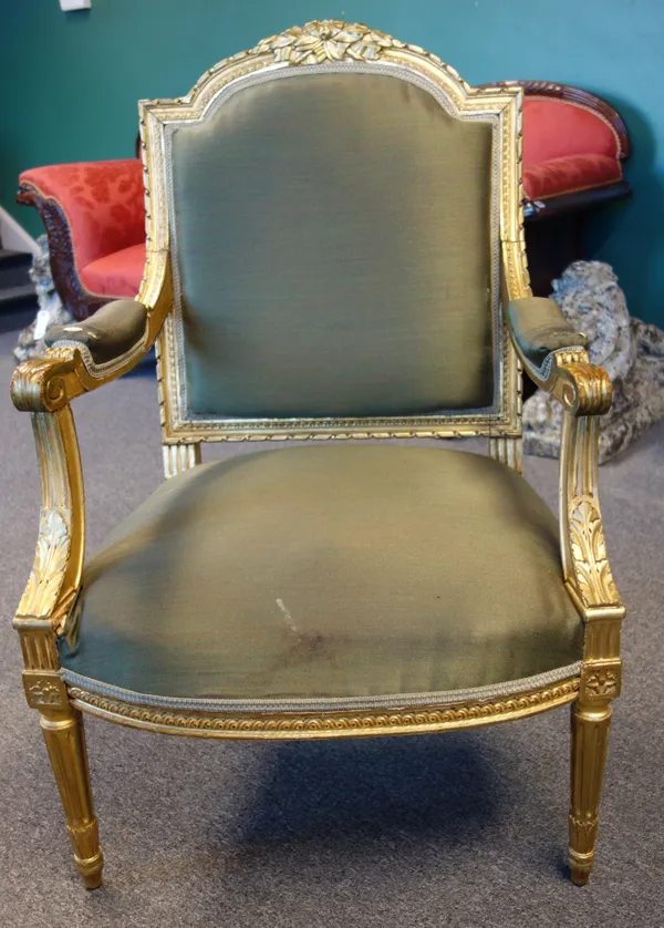 A pair of late 19th century French Louis XVI style gilt framed open armchairs, with ribbon tied floral crest and bow seat, on tapering fluted supports