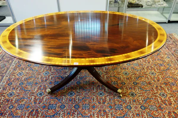 A George III style satinwood banded mahogany oval centre table, the snap top on turned column and four downswept supports, 167cm wide x 73cm high x 11