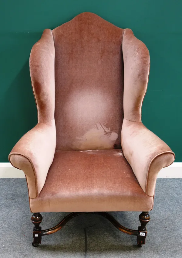 A George I style walnut framed wing back armchair, on baluster turned supports united by shaped 'X' frame stretcher, 95cm wide x 137cm high x 85cm dee