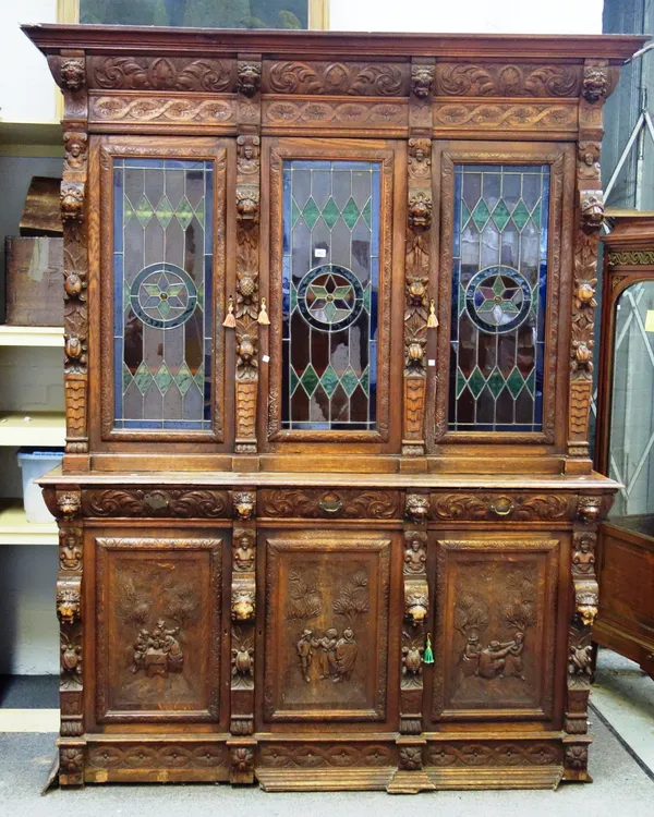 A 19th century Dutch carved oak bookcase cabinet, with three coloured leaded glass doors over three drawers and cupboards, on a plinth base, 191cm wid