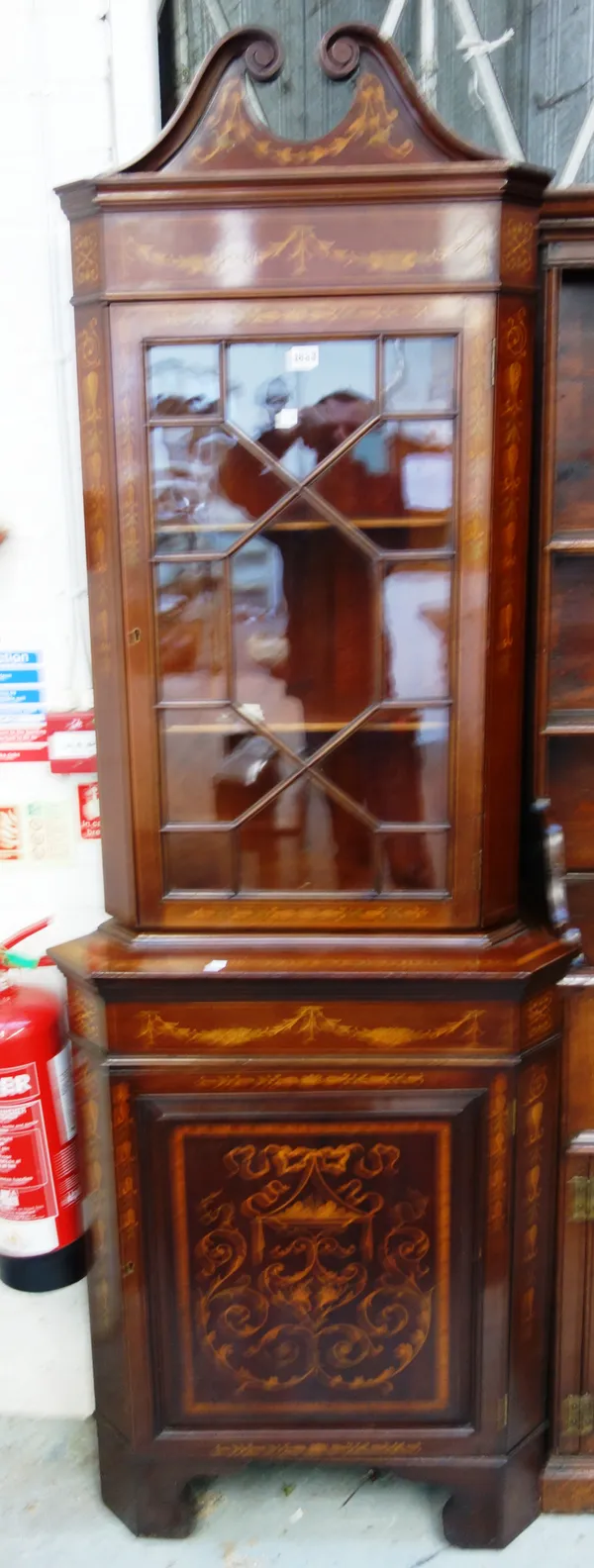 A near pair of late 19th century marquetry inlaid mahogany corner cabinets, each with swan neck cornice over astragal door and panel cupboard, on brac