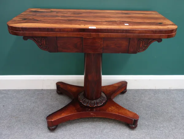 A George IV rosewood card table, the rounded rectangular top on turned column and quatrefoil platform, 88cm wide x 74cm high x 43cm deep.