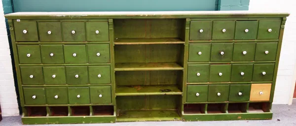 A large 20th century green painted apothecary cabinet, with three open shelves flanked by four rows of four drawers over eight pigeonholes, 308cm wide