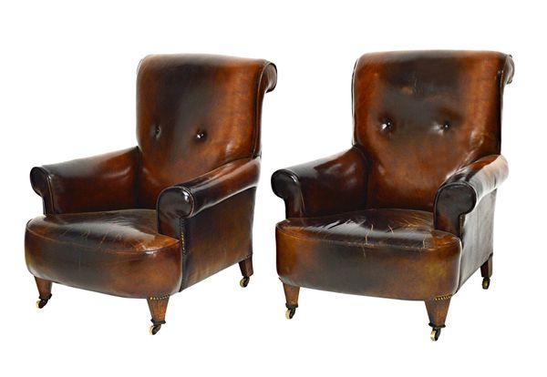 A pair of early 20th century brass studded brown leather upholstered easy armchairs, with roll over backs and arms, on tapering square supports, 86cm