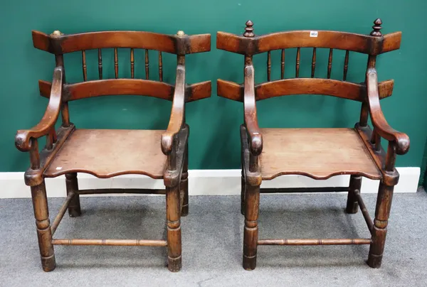 A pair of Senufo West African teak framed open armchairs, with solid seats and turned supports, 79cm wide x 89cm high x 58cm deep, (2).