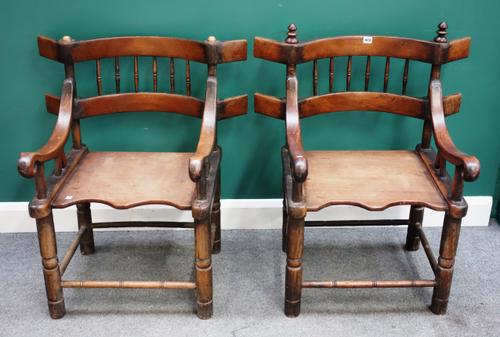 A pair of Senufo West African teak framed open armchairs, with solid seats and turned supports, 79cm wide x 89cm high x 58cm deep, (2).