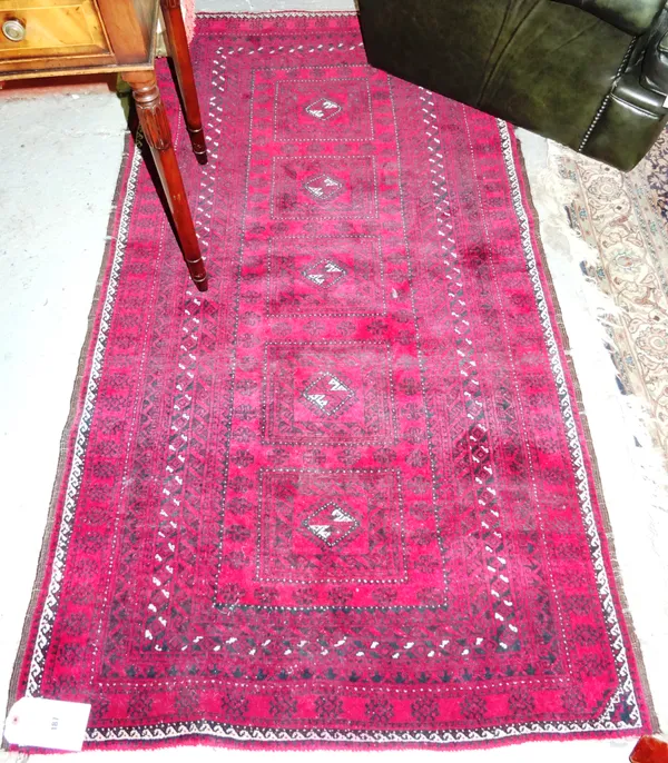 An Afghan rug, the madder field with a row of five hooked guls, in square medallions, a banded border, 100.5cm x 181cm. G5