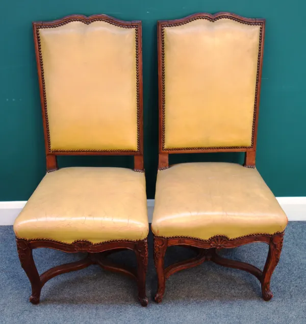 A set of twelve French 19th century stained beech dining chairs with studded leather upholstery on carved scroll supports united by X stretcher,(12).