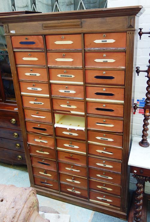 An early 20th century French walnut cartonnier, with three rows of twelve cartons, on plinth base, 135cm wide x 37cm deep x 218cm high.