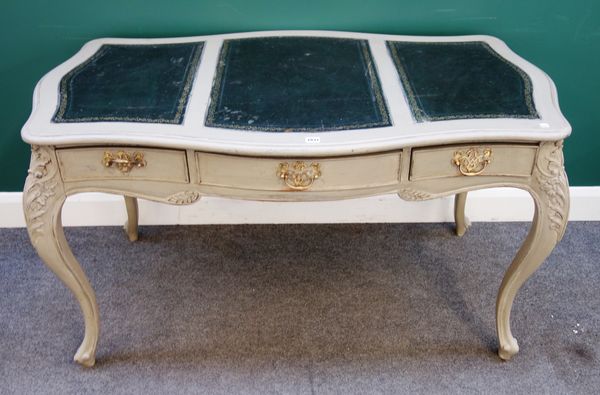 A grey painted Louis XV style writing desk, the serpentine top over three frieze drawers, on cabriole supports, 137cm wide x 77cm high x 76cm deep.