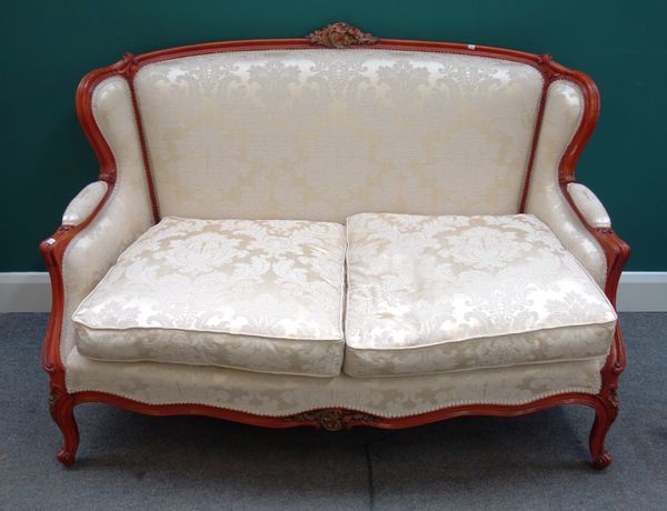 A pair of Louis XV style parcel gilt walnut framed two seat sofas, with serpentine seats, on scroll feet, 140cm wide x 97cm high x 85cm deep, (2).