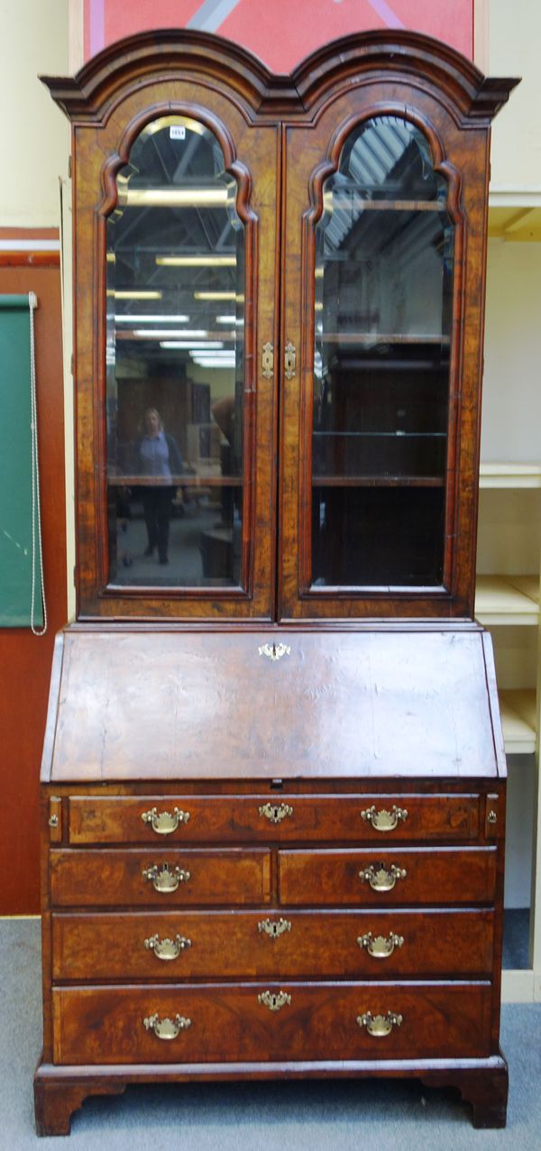 A George II figured walnut bureau bookcase, the double domed top over a pair of bevelled glazed arch top doors, the fall with fitted interior over one