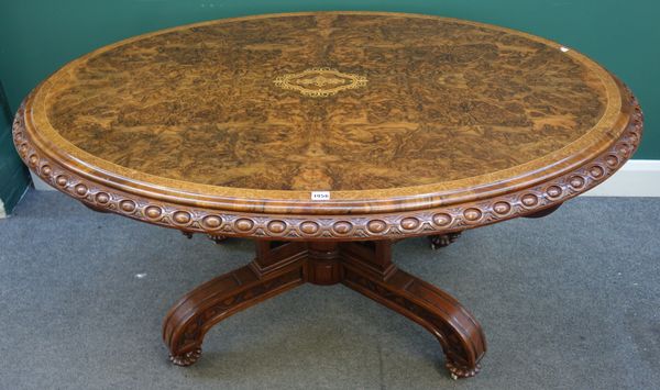 A Victorian marquetry inlaid figured walnut centre table, the oval top with egg and dart rim on carved and pierced base and four downswept supports ch