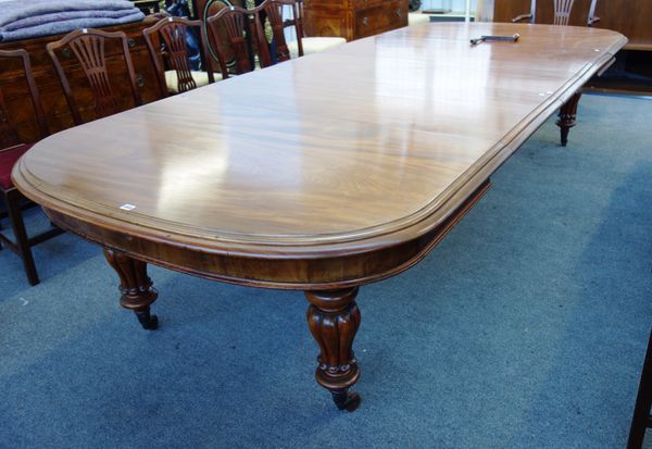 A Victorian mahogany extending dining table, the rounded rectangular top on a pair of tulip carved baluster supports, to include three extra leaves, 1