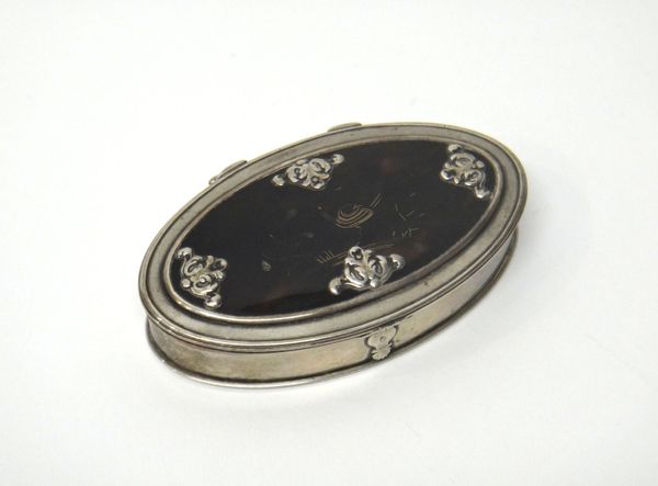 An 18th century silver mounted oval hinge lidded snuff box, gilt within, the tortoiseshell lid decorated with a wirework bird motif to the centre and