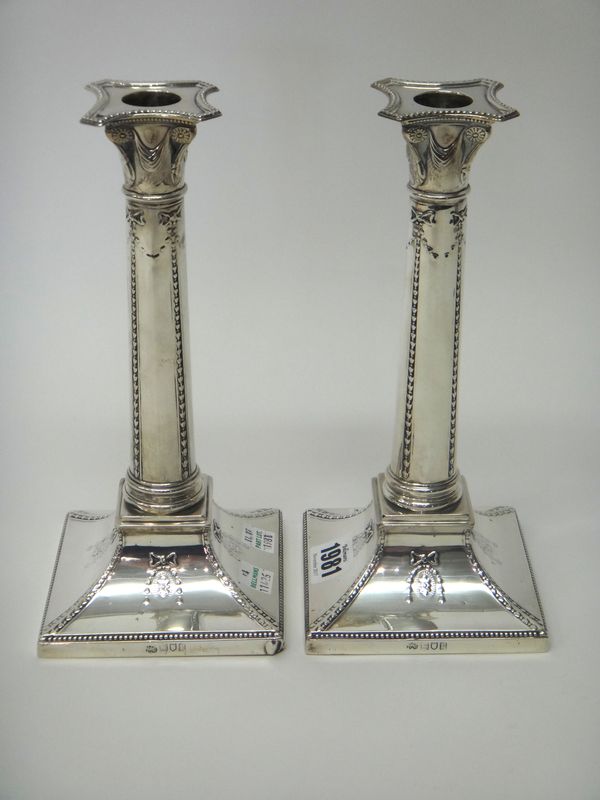 A pair of silver table candlesticks, each designed as a Classical column, raised on a swept square base, loaded, London 1912, height 23.5cm.