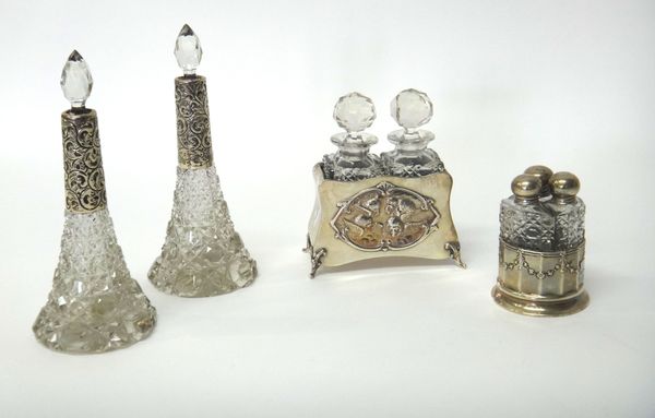 A pair of faceted glass scent bottles, with stoppers, with a Victorian silver twin compartment stand, embossed with shaped oval panels, depicting cher