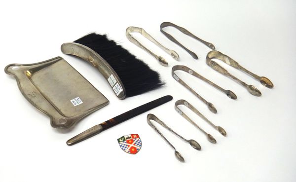 Six pairs of silver sugar tongs, various designs, a Sterling crumb tray, a silver mounted curved brush, Birmingham 1939, a silver handled tortoiseshel