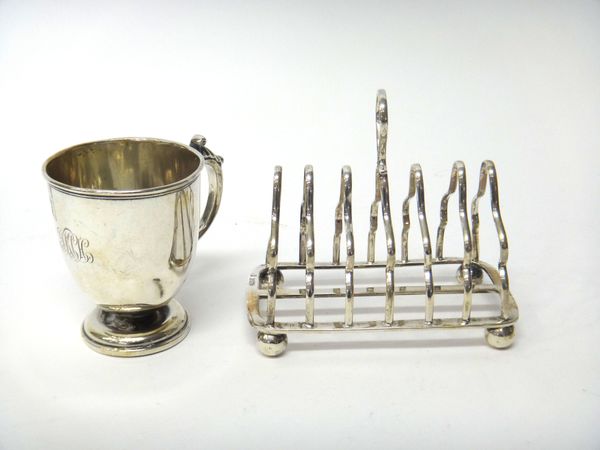 Silver, comprising; a seven bar toast rack, having a loop shaped handle, raised on four spherical feet, Sheffield 1912 and a christening mug raised on