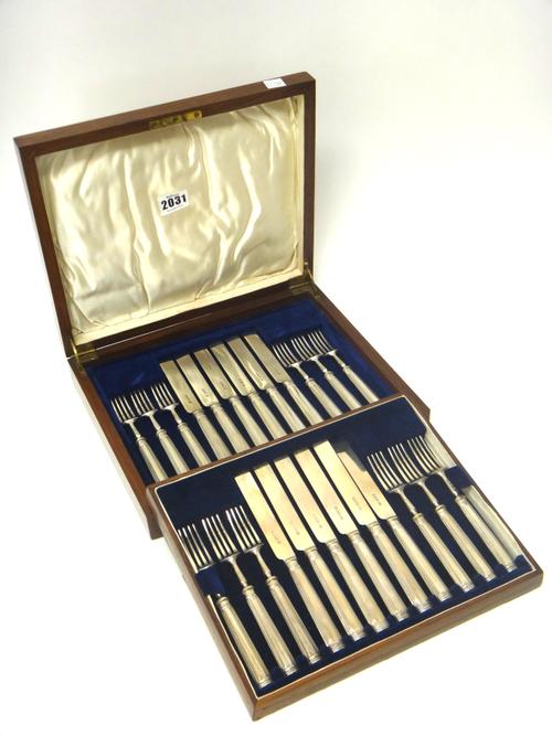 A set of twelve pairs of silver dessert or fruit knives and forks, having loaded silver handles, Sheffield 1929, with a fitted wooden case, having a k