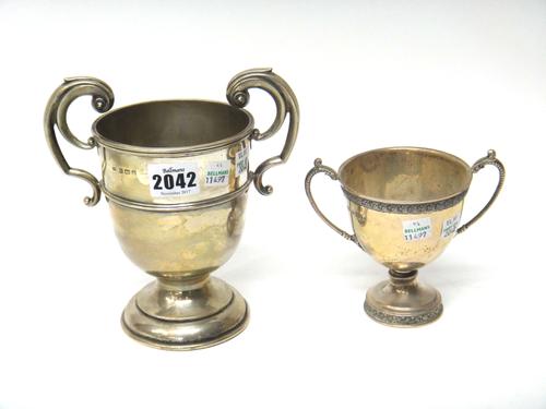 A silver twin handled trophy cup, with scrolling handles, raised on a circular base, Birmingham 1907 and a silver twin handled smaller trophy cup, hav
