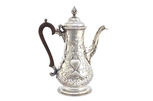 An early George III silver coffee pot, of baluster form, with embossed floral, foliate and vase decoration, the front with a shaped oval cartouche in