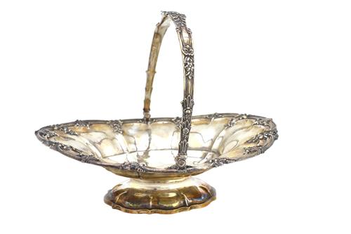A George IV silver cake or fruit basket, of shaped oval form, decorated with a bold floral and scrolling pierced rim and with a swingover handle, rais