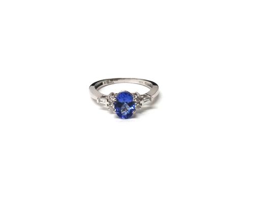 An 18ct white gold, diamond and tanzanite ring, the central oval cut claw set tanzanite flanked on each side with two round brilliant and one baguette