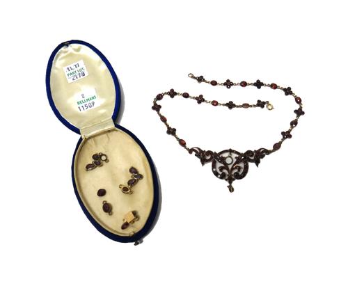 A Bohemian garnet set necklace, the front in a pierced openwork design, the chain with flowerhead shaped motifs, alternating with oval cut garnets, on