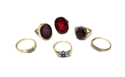 A gold and platinum, garnet and diamond set oval cluster ring, claw set with the oval cut garnet at the centre, in a surround of circular cut diamonds