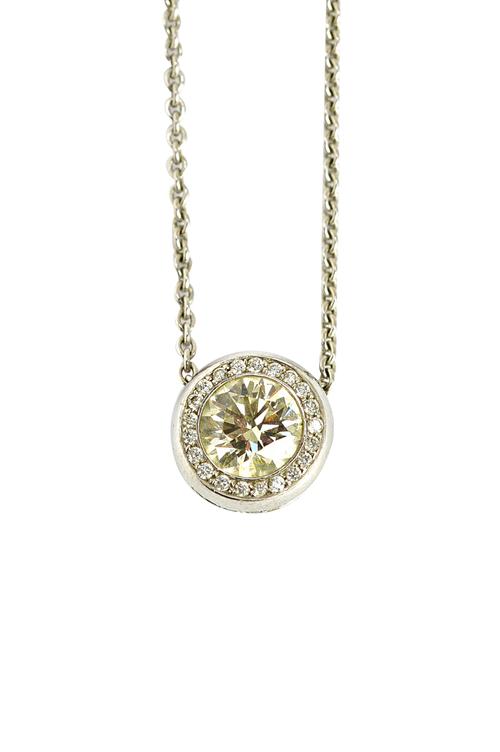 A white gold and diamond pendant, collet set with the principle circular cut diamond in a surround of smaller cut diamonds, the principle diamond weig