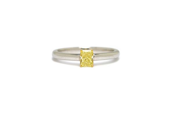 A treated(?) yellow diamond solitaire ring, the princess cut yellow diamond weighing approximately 0.30 cts, claw set in yellow metal to a white metal