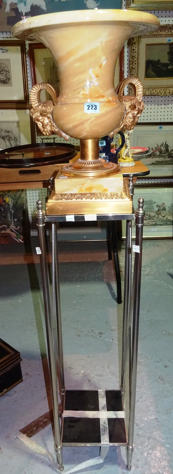 A 20th century gilt metal mounted marble urn with rams head handles on later chrome jardiniere stand. (2) D2