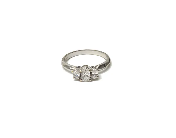 An 18ct gold three stone diamond ring, the central oval cut diamond between two smaller oval cut diamonds, the shank stamped '052', ring size M and a