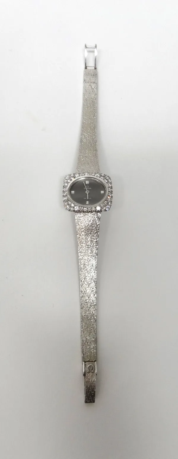 An Omega De Ville 18ct white gold and diamond set lady's dress bracelet wristwatch, the signed oval grey dial with baton numerals at 3, 6, 9 and 12, t