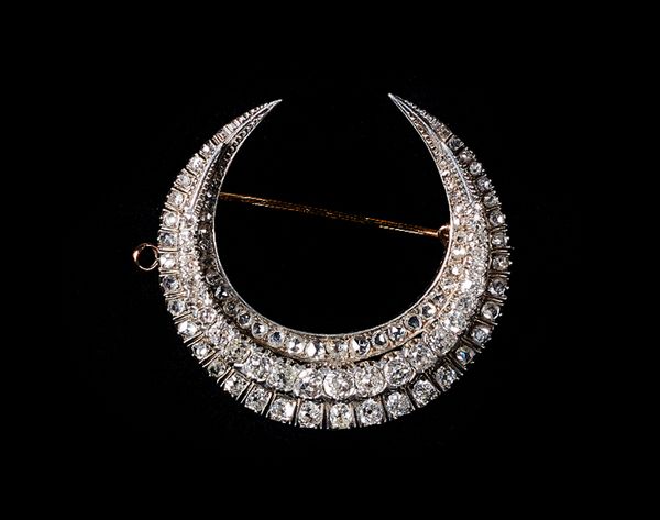 A Victorian diamond brooch, designed as a crescent, mounted with a row of graduated cushion shaped diamonds to the centre, in a raised design, with an