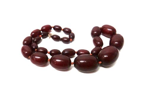 A single row necklace of graduated oval dark red amber beads, on a boltring clasp, length of necklace 45cm, gross weight 45.5 gms.