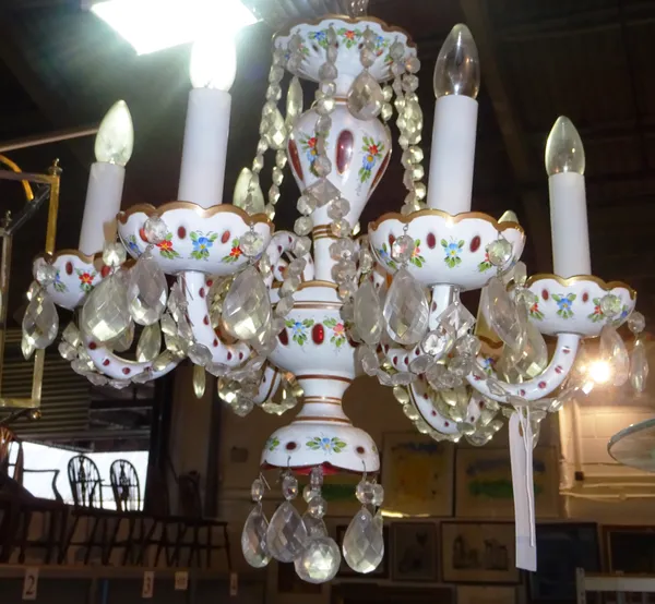 A Bohemian enamelled cranberry glass six branch chandelier, 20th century, the baluster stem issuing six swan neck arms, hung with cut glass chains and
