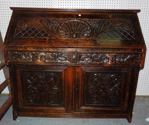 A 19th century carved oak student's bureau, over a cupboard base, 118cm wide x 106cm high. M11