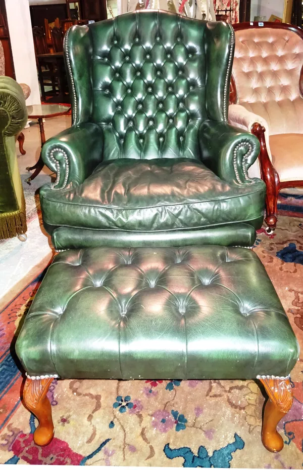 A 20th century green leather mahogany framed wingback armchair, with matching footstool, (2). E5
