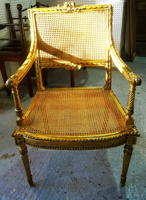 A Victorian giltwood bergère armchair, the rectangular caned back surmounted by ribbon and rose carving, on spiral fluted legs. A9