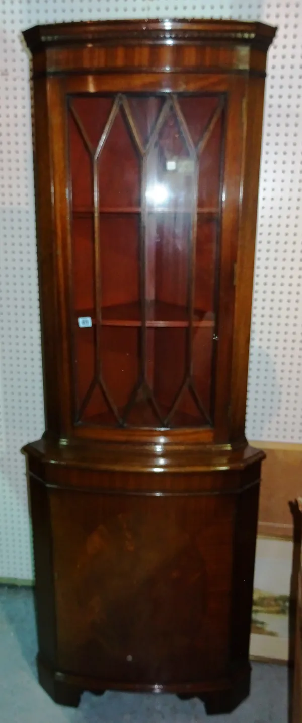 A mahogany corner cupboard in the Georgian style, the dentil moulded cornice above an astragal glazed door, with a cupboard below, on bracket feet, 64