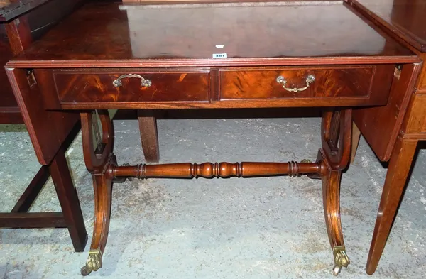 A mahogany, cross-banded and ebony strung drop-flap sofa table, in the Regency style, with brass lion paw cappings and castors, 143cms wide overall. K