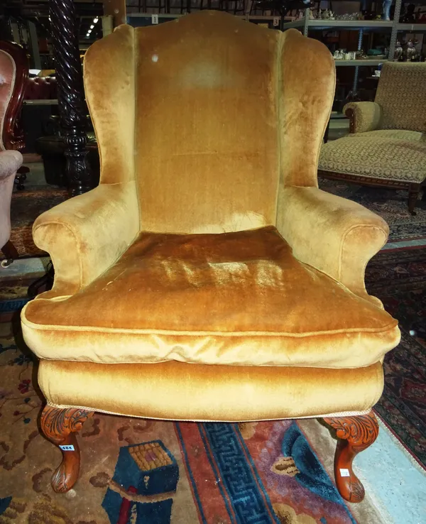A mahogany and gold/brown upholstered wing armchair, in the Georgian style, on cabriole legs. E4