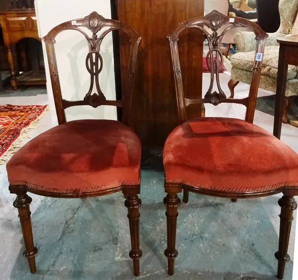 A set of three Victorian walnut dining chairs, the arched backs with pierced foliate carved and oval moulded vertical splats, upholstered in maroon, t