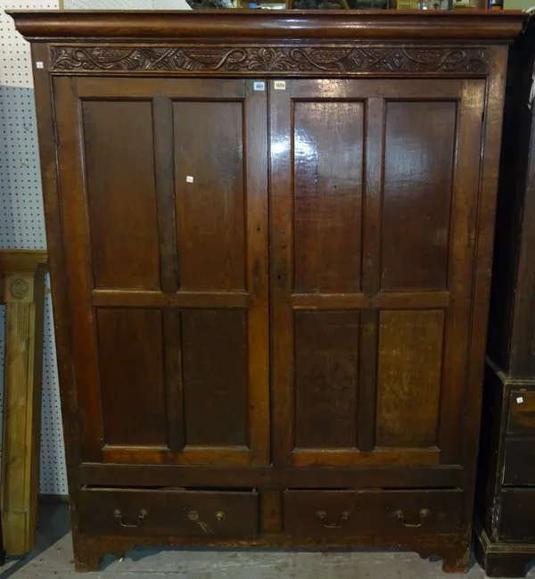 A 17th century oak wardrobe, with carved frieze over a pair of four panelled doors and drawers, on block feet, 150cm wide x 186cm high. M8