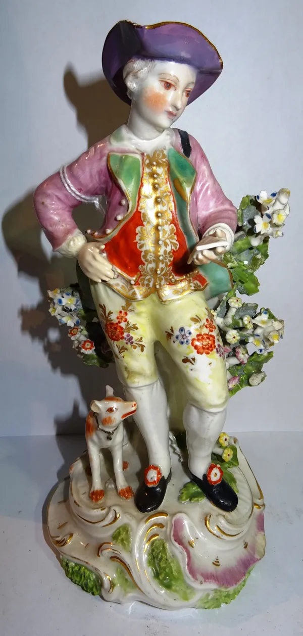 A Derby porcelain figure, circa 1765, modelled as a gallant in a tricorn hat, reading verse, with a dog at his feet, floral bocage behind on a gilt sc
